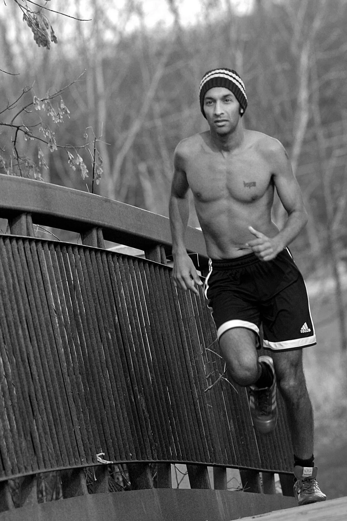 Black-and-white photo of Dr. Sanjeev Goel running across a wooden footbridge — closing image of the About page