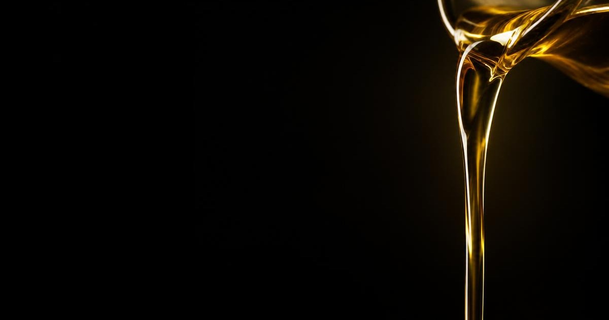 A stream of golden cooking oil pouring against a dark background